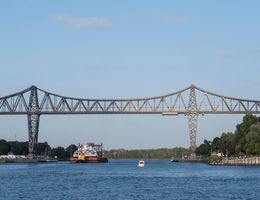 Eine Schwebefähre überquert den Nord-Ostsee-Kanal unter einer großen Stahlbrücke.